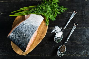 Siyah ahşap arka planda Atlantik çiğ somon, biftek ve maydanoz delikanlı