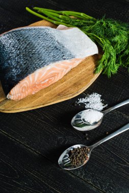 Siyah ahşap arka planda Atlantik çiğ somon, biftek ve maydanoz delikanlı