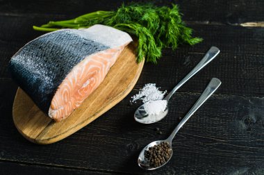 Siyah ahşap arka planda Atlantik çiğ somon, biftek ve maydanoz delikanlı