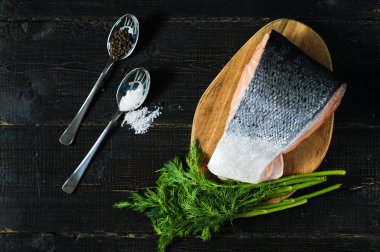 Siyah ahşap arka planda Atlantik çiğ somon, biftek ve maydanoz delikanlı