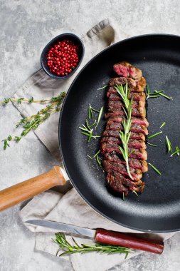 Sığır eti biftek tavada kavrulmuş arka. Gri arka plan, üst görünüm.