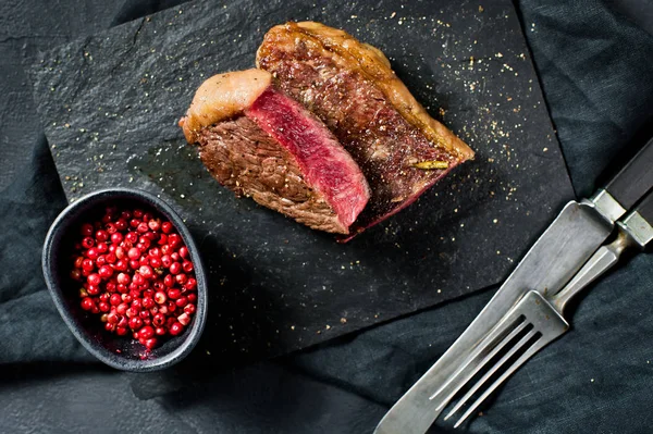 Steak de surlonge de boeuf, rôti à l'arrière. Fond noir, vue de dessus . — Photo