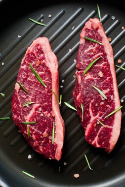 Izgara tavasında sığır eti bifteği. Siyah arka plan, üst görünüm.