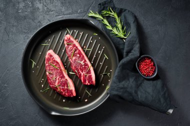 Mermer sığır bifteği siyah Angus ızgara tavada. Siyah arka plan, üst görünüm.