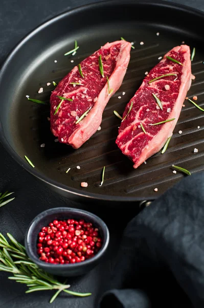 Na pánvi na grilu černý steak z mramoru. Černé pozadí, pohled shora. — Stock fotografie