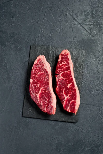 sirloin a raw beef steak. Black background, top view.