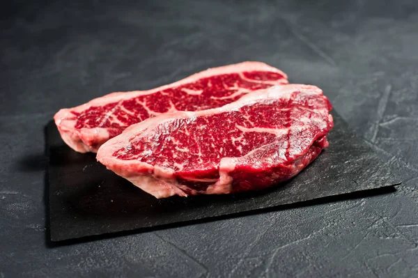 sirloin a raw beef steak. Black background, top view.