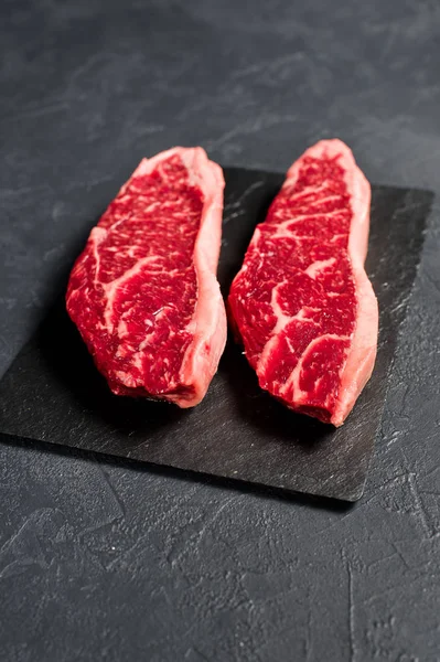 霜降り牛肉ブラックアンガスのステーキ。黒の背景、上面図. — ストック写真