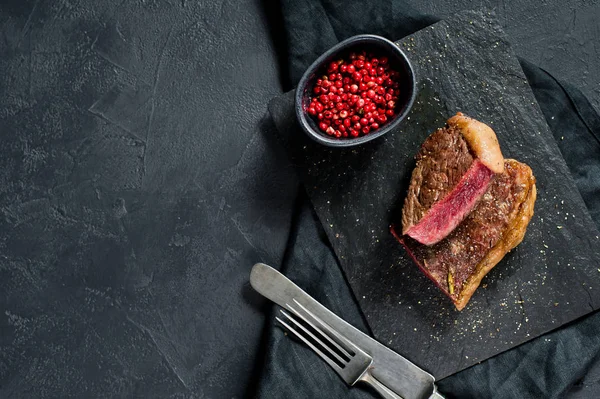 Steak de surlonge de boeuf, rôti à l'arrière. Fond noir, vue de dessus . — Photo