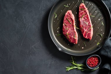 Izgara tava üzerinde Beef rampa biftek. Siyah arka plan, üst görünüm.