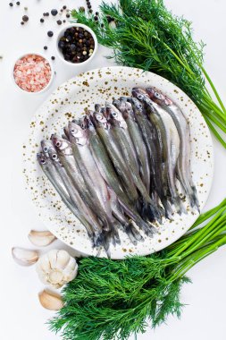 Bir tabakta çiğ uskumru, dereotu, pembe tuz, biber ve sarımsak. Beyaz arka plan, üst görünüm, metin için alan.