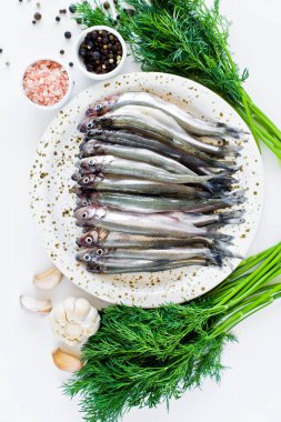 Çiğ bir tabak, dereotu, pembe tuz, biber ve sarımsak üzerinde kokuyordu. Beyaz arka plan, üst görünüm, metin için alan.