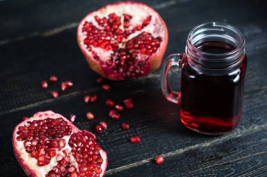 Olgun nar ve siyah ahşap arka plan üzerinde nar suyu bir bardak.