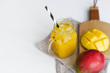 Olgun mango, yarım mango ve ahşap kesme Tahtası üzerinde bir tüp ile mango suyu bir bardak.