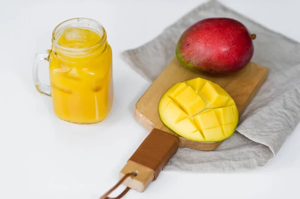 Ripe mango and a glass of mango juice on a wooden chopping Board.