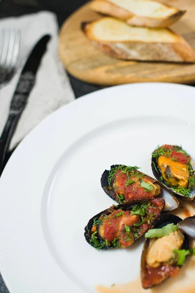 Baked mussels in tomato sauce with coriander and Parmesan on a white plate. — Stock Photo, Image