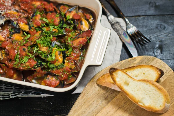 Kişniş ve Parmesan ile domates soslu pişmiş midye.