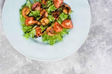 Gri arka planda ızgara karides ile yeşil salata.