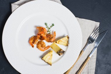 Kızarmış kral karidesli beyaz tabak ve ananas dilimleri..