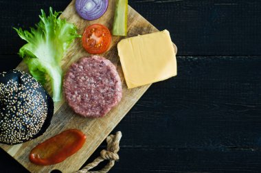 Ahşap doğrama Tahtası siyah Burger için Malzemeler, siyah arka plan.