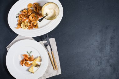 Siyah zemin üzerinde kızarmış kral karidesli beyaz tabak ve metin için boşluk.