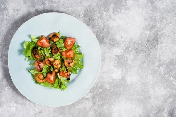 Grüner Salat mit gegrillten Garnelen auf grauem Hintergrund. — Stockfoto