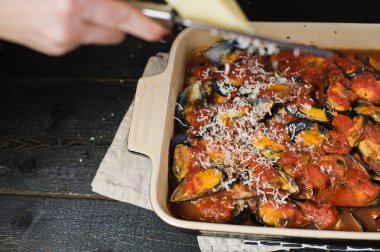 Şef domates soslu midye üzerine peynir sürüyor.