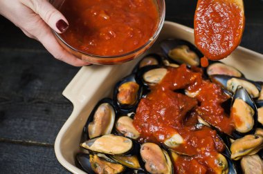 Siyah arka planda domates salçası ile çiğ midye, pişirme.