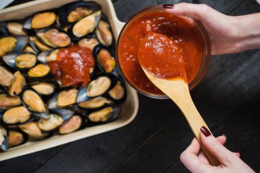 Siyah arka planda domates salçası ile çiğ midye, pişirme.