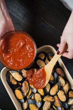 Siyah arka planda domates salçası ile çiğ midye, pişirme.