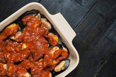 Siyah arka planda domates salçası ile çiğ midye, pişirme.