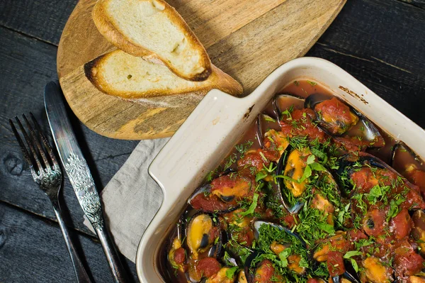 Kişniş ve Parmesan ile domates soslu pişmiş midye.