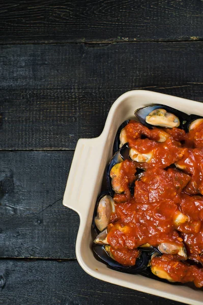 Siyah arka planda domates salçası ile çiğ midye, pişirme.