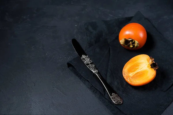 Persimmon on black fabric with space for text. — Stock Photo, Image