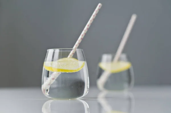 Vaso de agua clara con limón y paja . — Foto de Stock