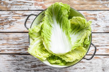 Kevaşe içinde taze Çin lahanası yaprakları. Beyaz ahşap arka plan. Üst görünüm.