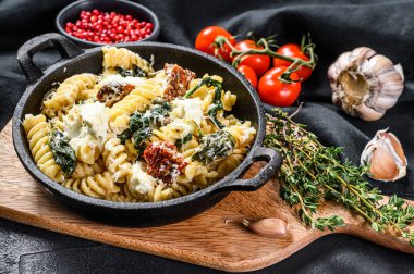 Ispanaklı Fusilli makarna, kurutulmuş domates ve tavada ricotta peyniri. Siyah arka plan. Üst görünüm.