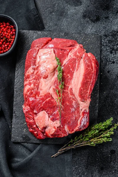 Raw Chuck eye roll steak. Organic beef. Black background. Top view.