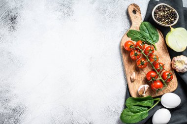 Ispanaklı omlet pişirme kavramı. Yumurta, soğan, sarımsak, domates, biber, ıspanak. Gri arka plan. Üst Manzara. Boşluğu kopyala.