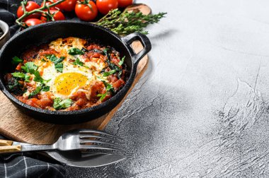 Ev yapımı shakshuka, kızarmış yumurta, soğan, dolmalık biber, domates ve tavada maydanoz. Gri arka plan. Üst Manzara. Boşluğu kopyala.