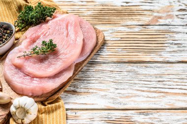 Tahtada kekik ve biberli taze hindi bifteği. Çiğ organik kümes hayvanları. Beyaz arka plan. Üst Manzara. Boşluğu kopyala.