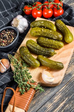 Salamura edilmiş salatalık turşusu ve kesme tahtasında baharatlar. Siyah arka plan. Üst görünüm.