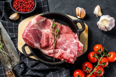 Kemiklerde çiğ domuz eti, tavada mermer biftek. Siyah arka plan. Üst görünüm.