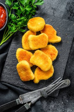 Tahtaya tavuk nugget ve ketçap sosu. Karanlık arka plan. Üst görünüm.