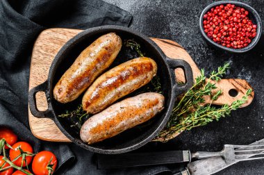 Dökme demir tavada domuz sosisi. Siyah arka plan. Üst görünüm.