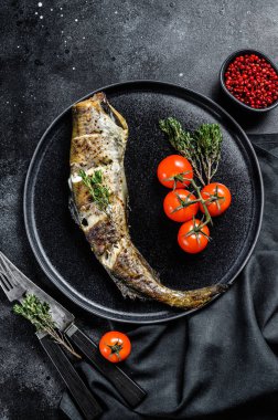 Lezzetli ızgara balık, taze kekik ve domates. Siyah arka plan. Üst görünüm.