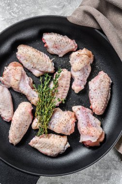 Tavada baharat ve otlarla marine edilmiş tavuk kanatları. Gri arka plan. Üst görünüm.