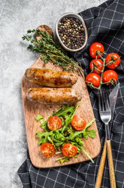 Mangalda ızgara sosis ve domates ve roka ile doğranmış. Gri arka plan. Üst görünüm.