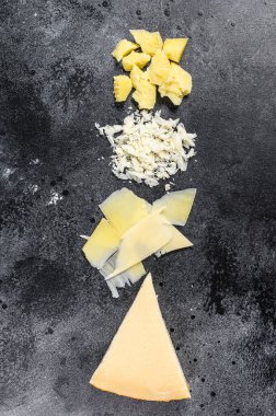 İtalyan sert parmesan peyniri dilimi, kesilmiş, rendelenmiş. Siyah arka plan. Üst görünüm.