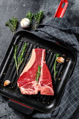 Tavada biftek var. Organik çiğ Tbon eti. Siyah arka plan. Üst görünüm